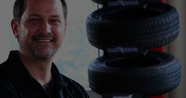smiling mechanic in front of tires